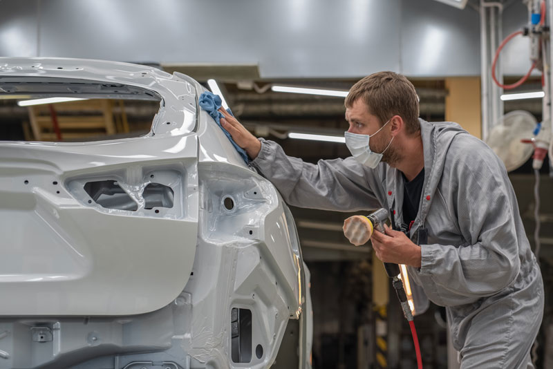 An employee of the paint shop of an automobile plant polishes the painted surface
