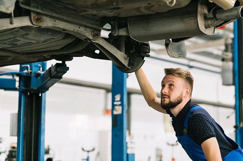 Auto mechanic looking under a car